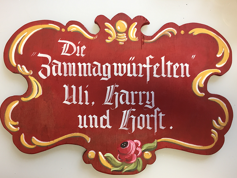 Pinselhandschrift und rustikale Bauernmalerei auf in Form gesägten Holzschild